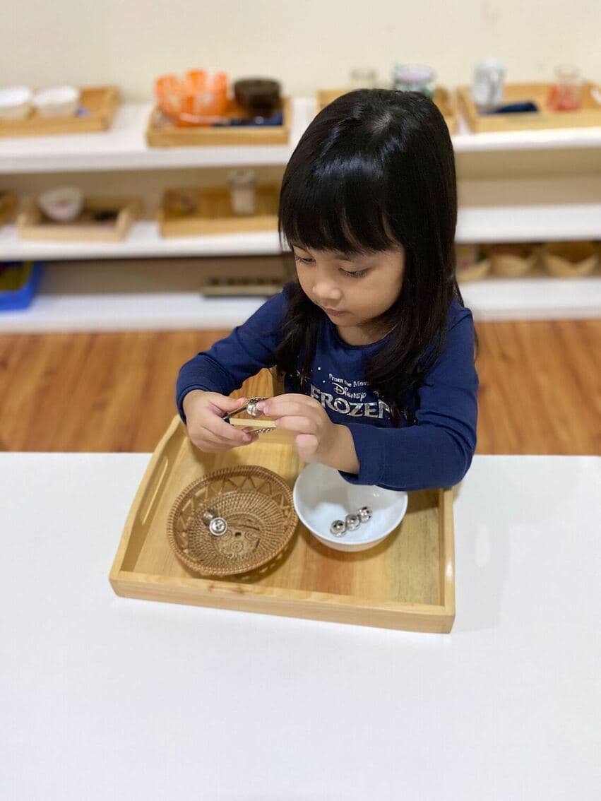 a student learning using one of practical life material