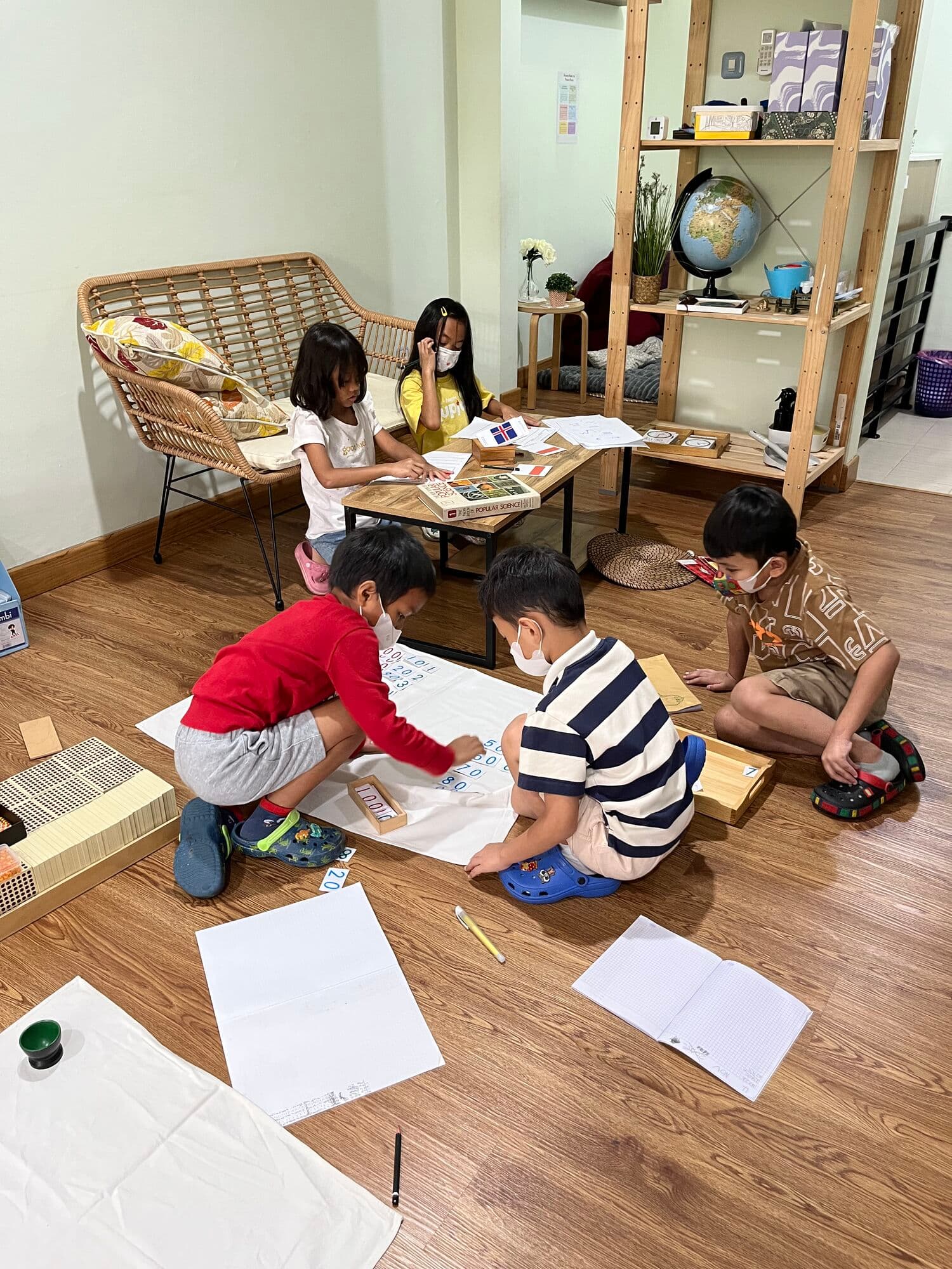 Children working on individual art and Montessori activities on the classroom floor